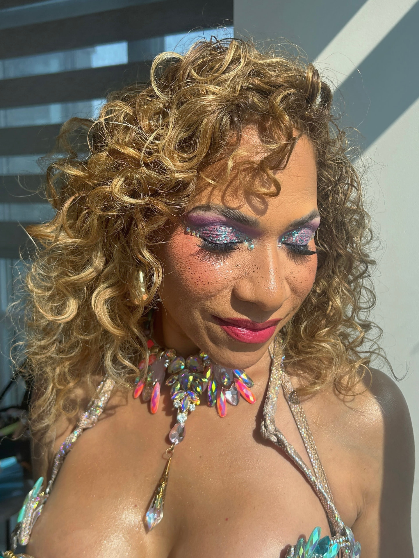 Purple glitter eye makeup with bold fuchsia lips in warm sunlight